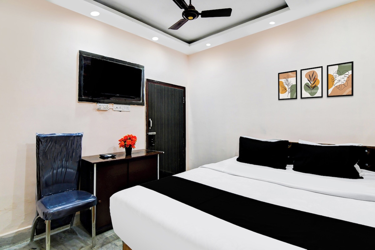 Een hotelkamer met een bed, een bureau met stoel, een televisie en kunst aan de muur.