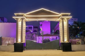 A gated entrance with a neoclassical archway and a vehicle parked inside. - Townhouse Mandarmani Beach (Kanthi)