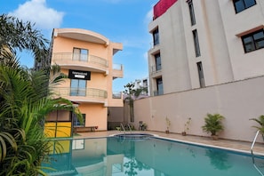 A pool area with a building labeled 'TOWNHOUSE' and a clear sky. - Townhouse Mandarmani Beach (Kanthi)
