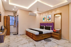 A hotel room with a bed, a desk, a mirror, and a ceiling fan. - Townhouse Mandarmani Beach (Kanthi)