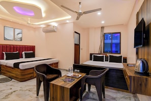 A hotel room with a bed, a desk, a chair, a television, and an air conditioning unit. - Townhouse Mandarmani Beach (Kanthi)