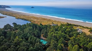 A coastal property with a swimming pool, dense forest, and a beach. - Wooded Lakefront Retreat (Port Orford)