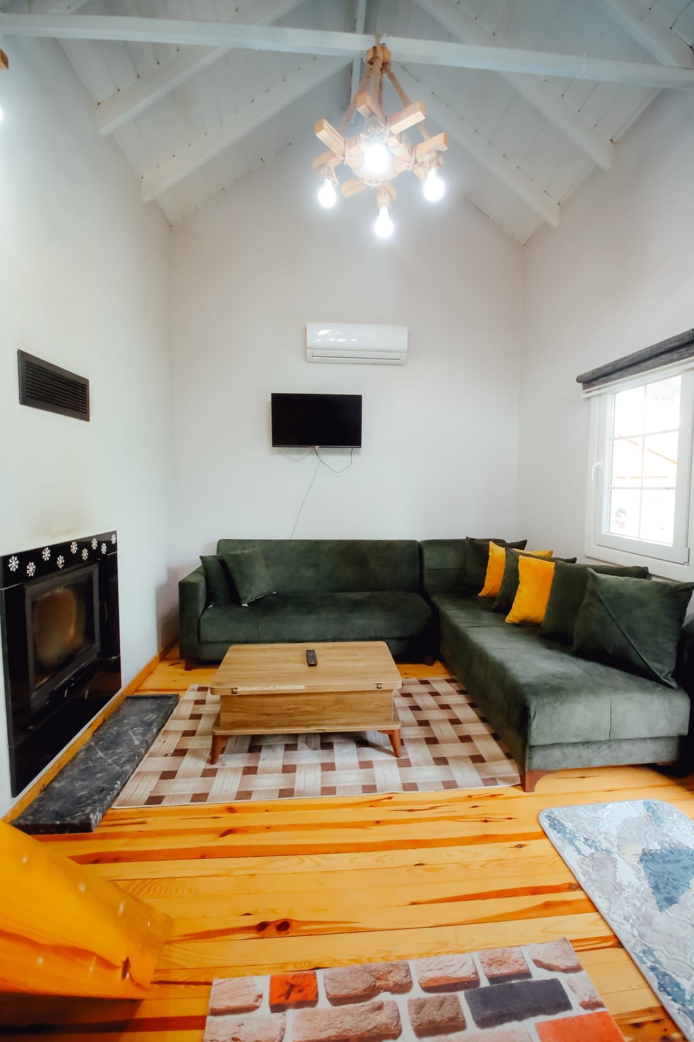 Una sala de estar con un sofá verde, una mesa de centro de madera, una chimenea y un ventilador de techo.