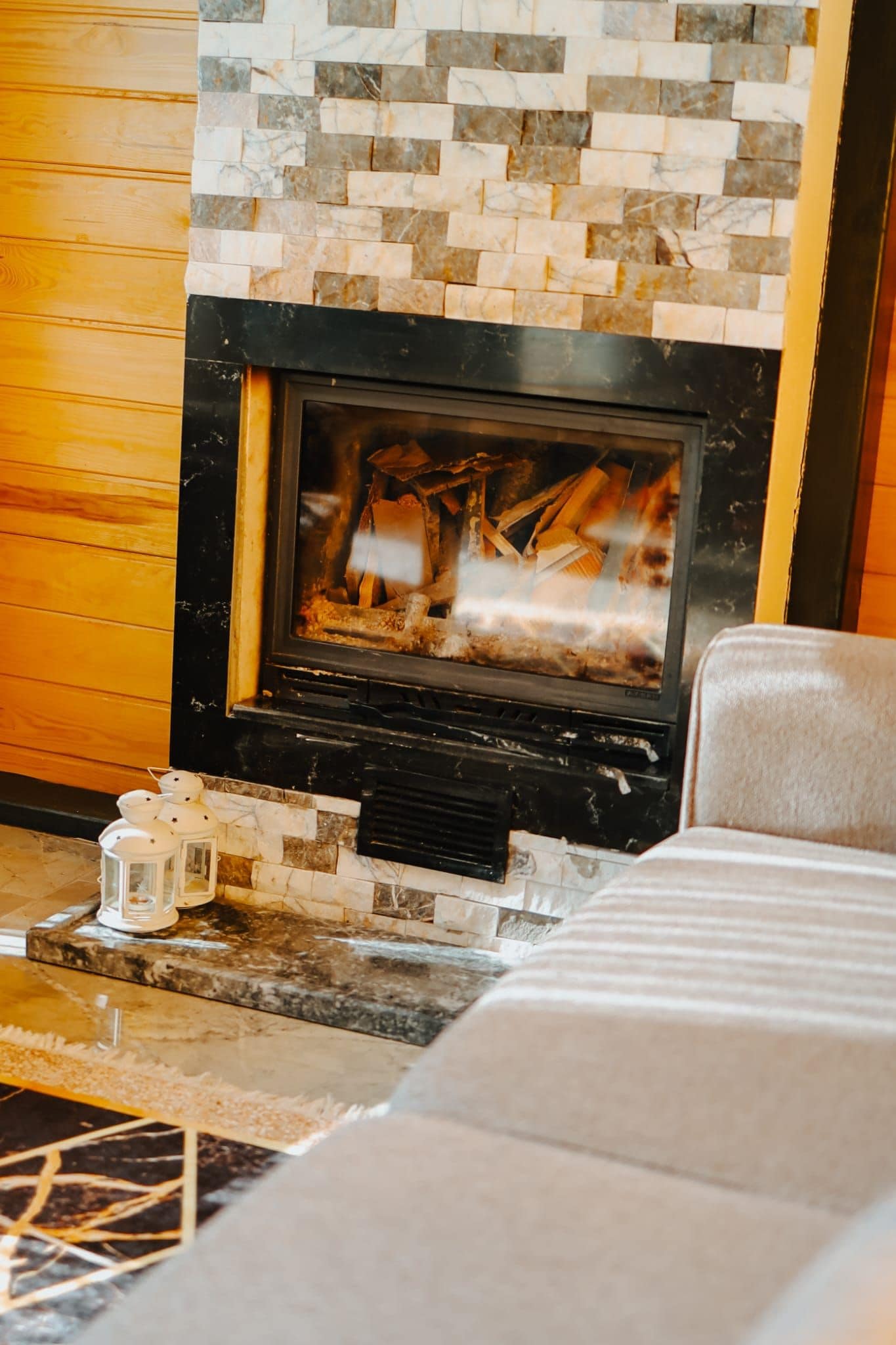A fireplace with a stone mosaic surround, a black hearth, and a visible fire.