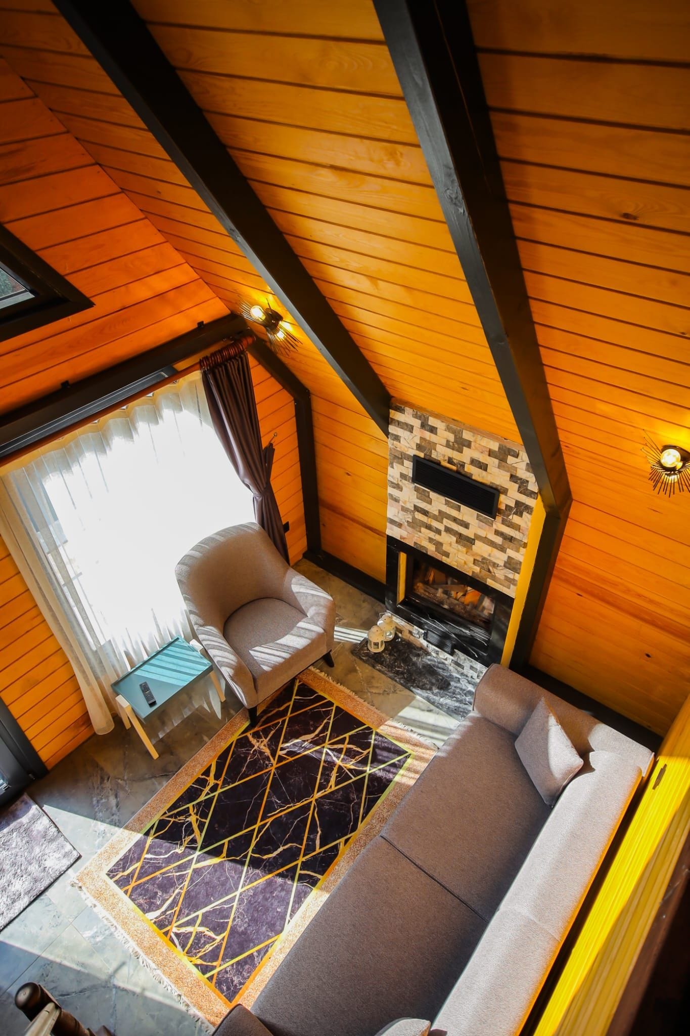Una habitación acogedora con techo de madera, chimenea, un sofá y una silla.
