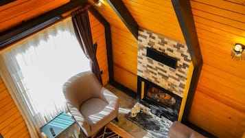 Una habitación acogedora con techo de madera, chimenea, un sofá y una silla.