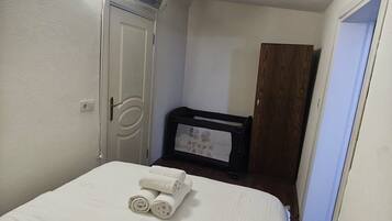 A hotel room with a bed, a wardrobe, a desk with a chair, and a mirror.