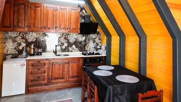 An attic kitchen with wooden cabinets, a stove, and a dining table set for two.