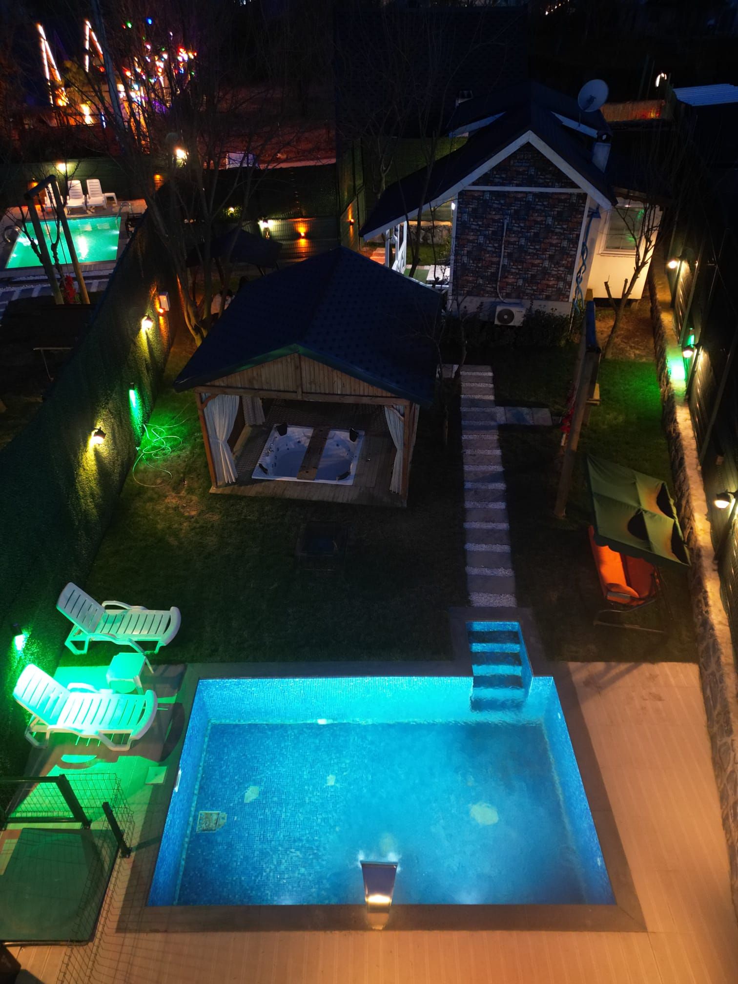 A swimming pool with a hot tub, lounge chairs, and a covered seating area.