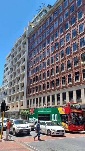 Un immeuble à plusieurs étages, dont la façade est un mélange de briques et de surfaces blanches, avec de grandes fenêtres et une entrée bien visible au niveau de la rue.
