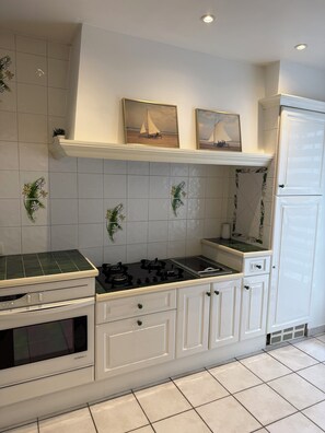Una cucina con mobili bianchi, un fornello e un frigorifero.