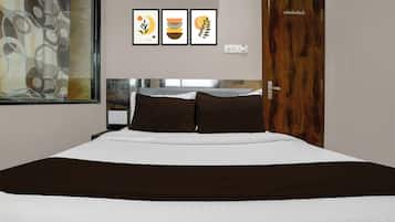 Habitación de hotel con una cama, una puerta de madera y tres cuadros en la pared.