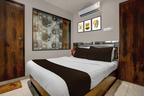 Un dormitorio con cama, una ventana con vistas, aire acondicionado de pared y un cuadro enmarcado.