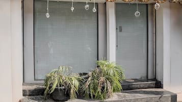Una entrada de edificio con dos puertas cerradas, un escalón que conduce a la entrada y una guirnalda de flores secas sobre las puertas.