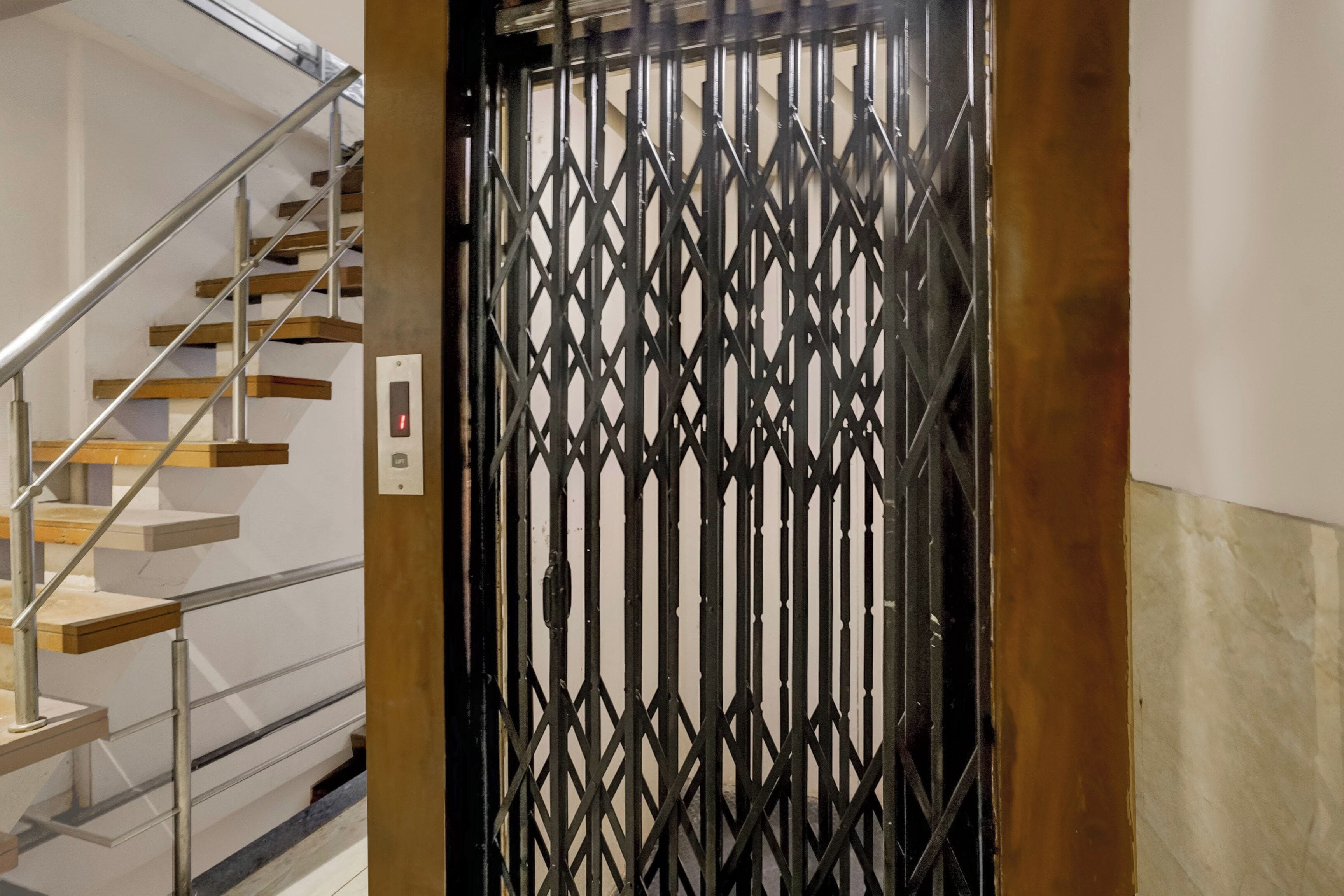Una escalera con barandilla metálica y una reja decorativa negra.