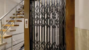 Una escalera con barandilla metálica y una reja decorativa negra.