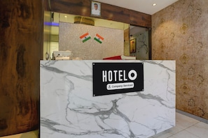 Mostrador de recepción de hotel con encimera de mármol y un letrero que indica servicio corporativo.