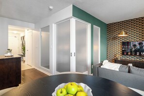A modern living room with a dining area, a sofa, a TV, and a decorative wall. - Fort York 1BR, Balcony Near the Waterfront (Toronto)