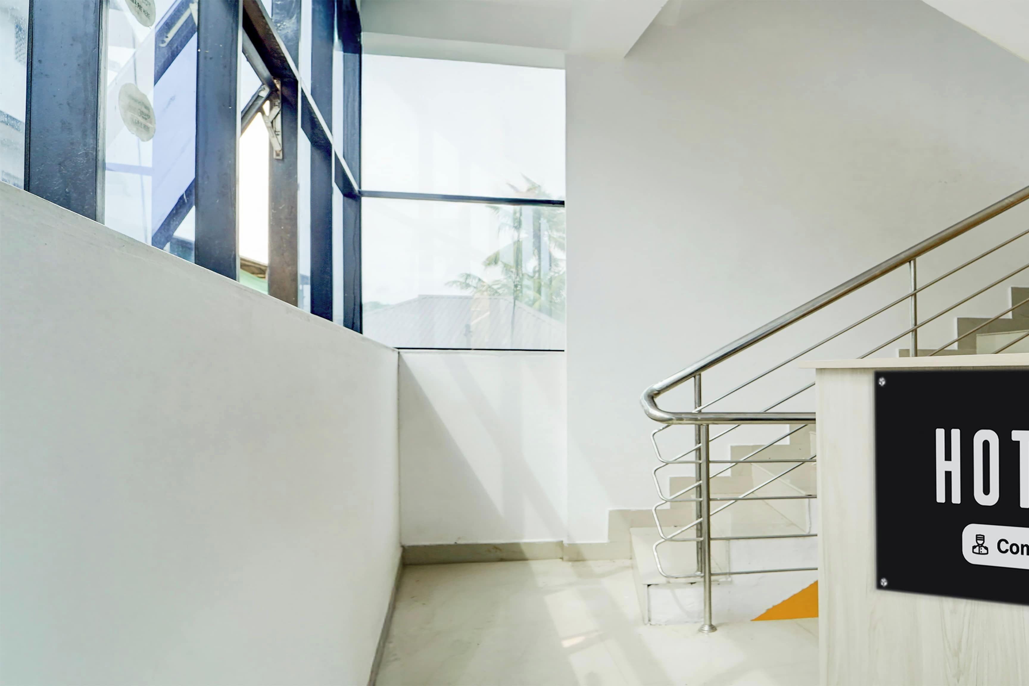 Interior moderno de un hotel con una escalera, un letrero que indica una sala de conferencias y vistas a través de una ventana.