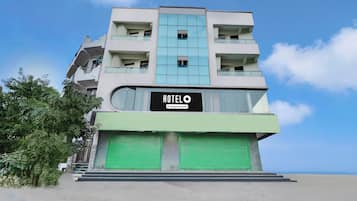 Un hotel de varios pisos con un llamativo letrero que dice 'HOTEL' en la fachada, con un diseño arquitectónico moderno que incluye balcones y ventanas amplias.
