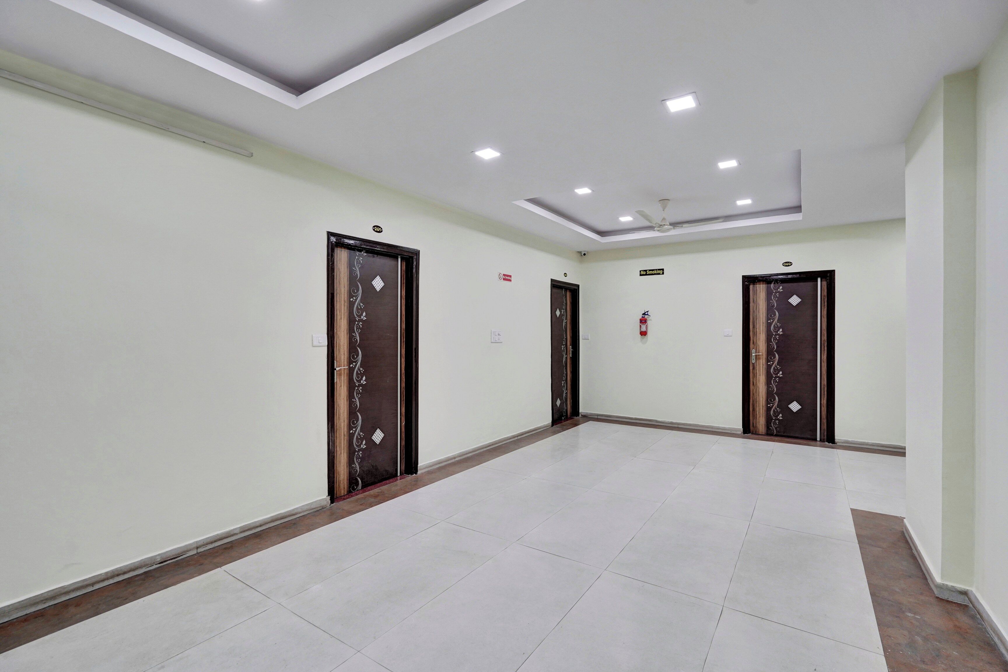 Un couloir avec quatre portes, chacune ornée d’un motif décoratif, et un plafond doté d’un éclairage encastré.