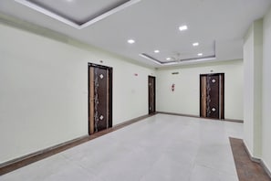 A hallway with four doors, each with a decorative pattern, and a ceiling with recessed lighting.