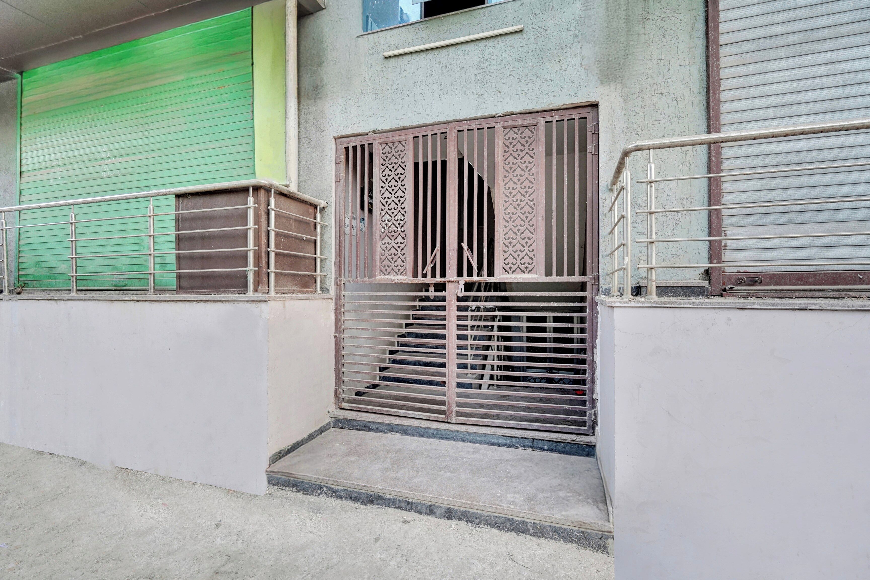 Una entrada protegida con un portón metálico y una escalera que lleva a un edificio.