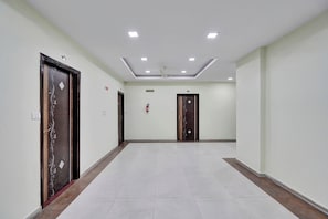 A hallway with two doors, a ceiling fan, and a fire extinguisher.