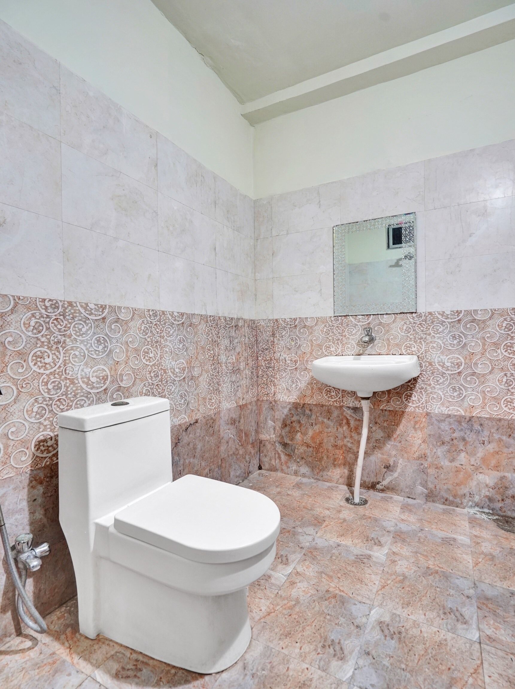 A bathroom with a toilet, sink, and patterned wall tiles.