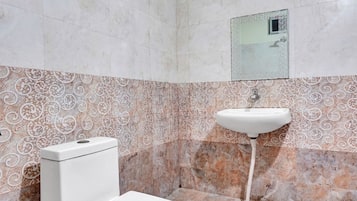 A bathroom with a toilet, sink, and patterned wall tiles.