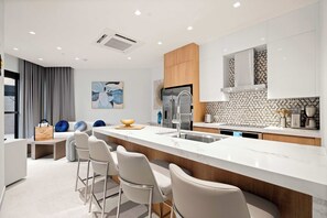 A modern kitchen with a central island, bar stools, a built-in oven, and a backsplash with hexagonal tiles. - Ground-Floor 1BR Retreat | Oversized Private Patio (Noord)