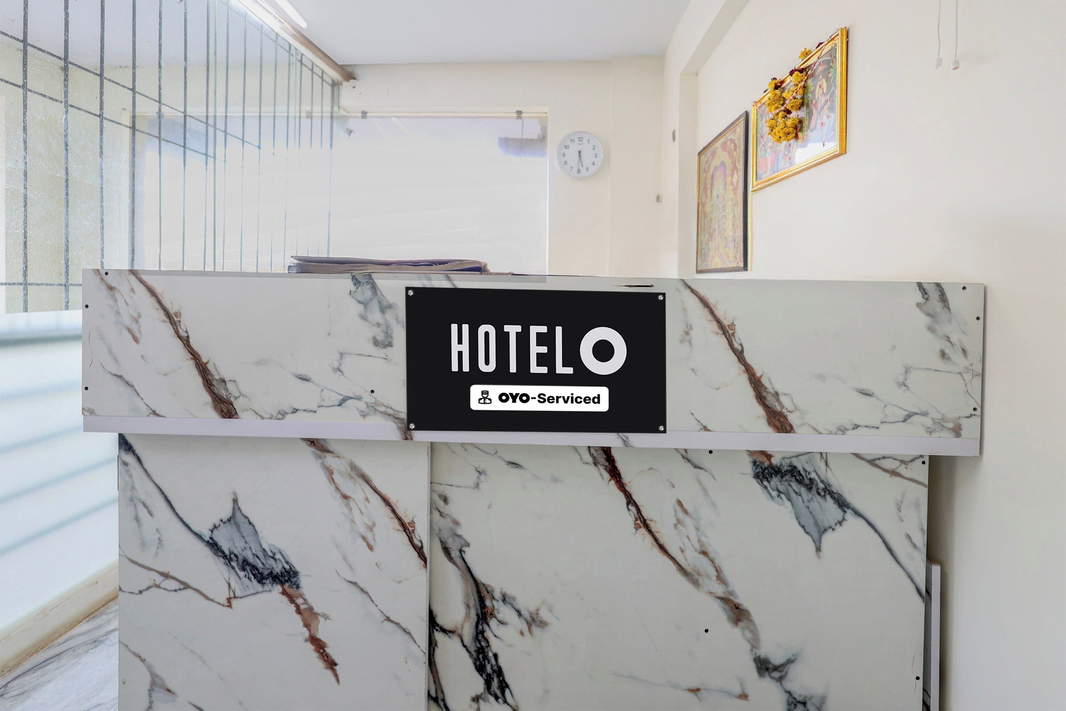 Uma receção de mármore com um letreiro a indicar 'HOTEL OYO-Serviced'.