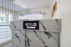 Una recepción con encimera de mármol y un cartel que indica servicio OYO.