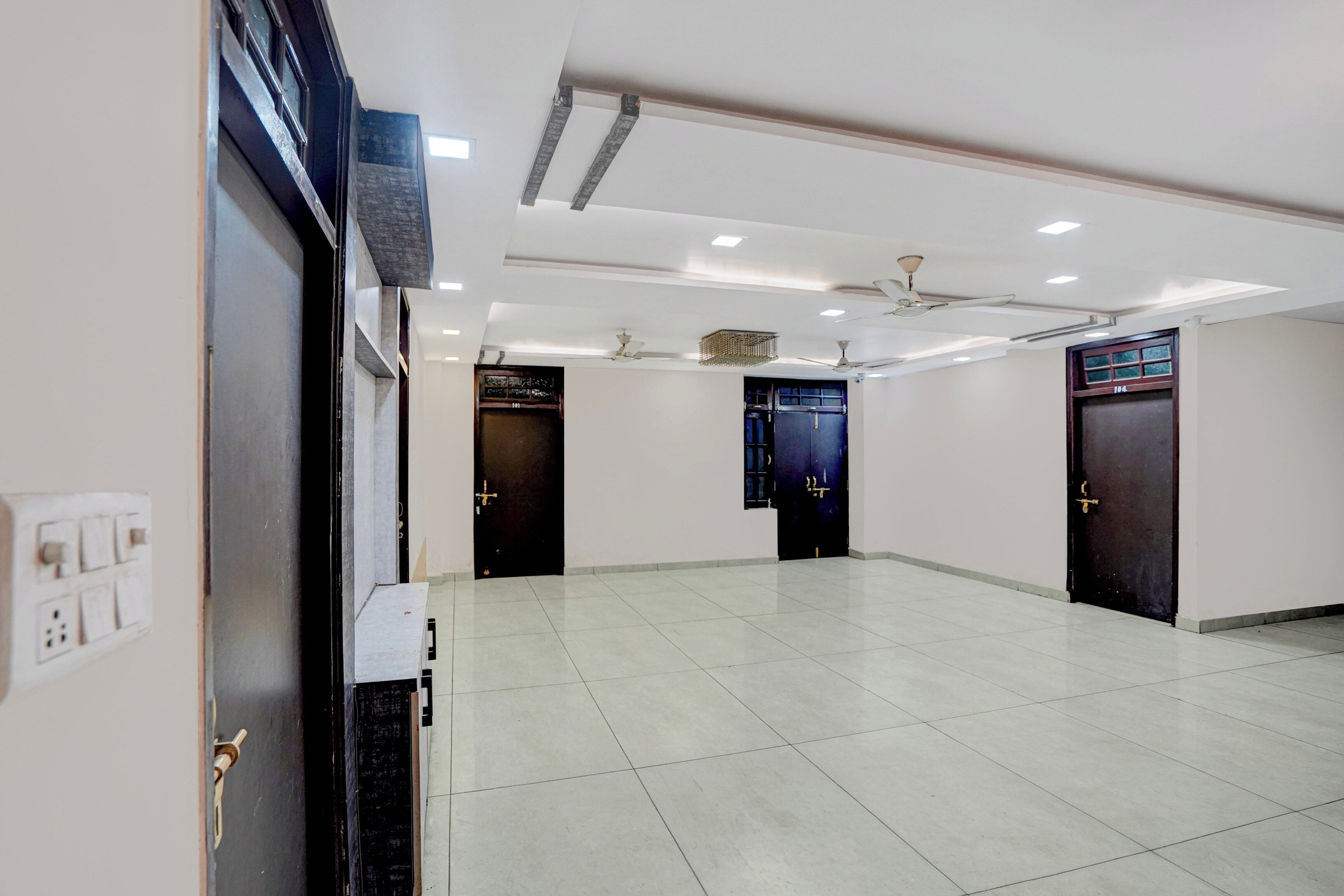 A spacious hallway with tiled flooring, multiple doors, and ceiling fans.