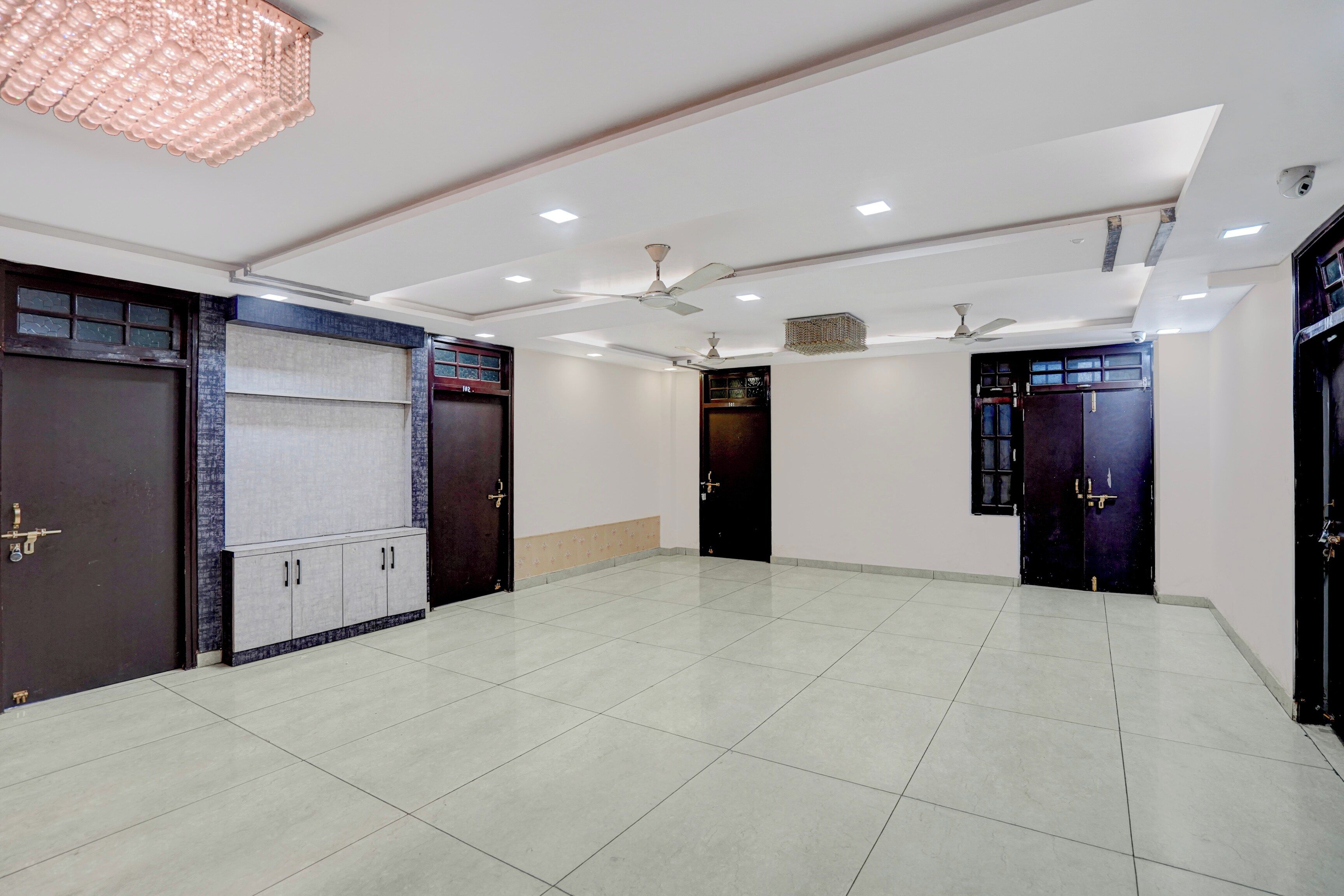 Una habitación amplia con suelo de baldosas, ventiladores de techo, iluminación empotrada y puertas de madera oscura.