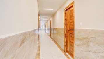 A long, narrow hallway with marble flooring and wooden doors.
