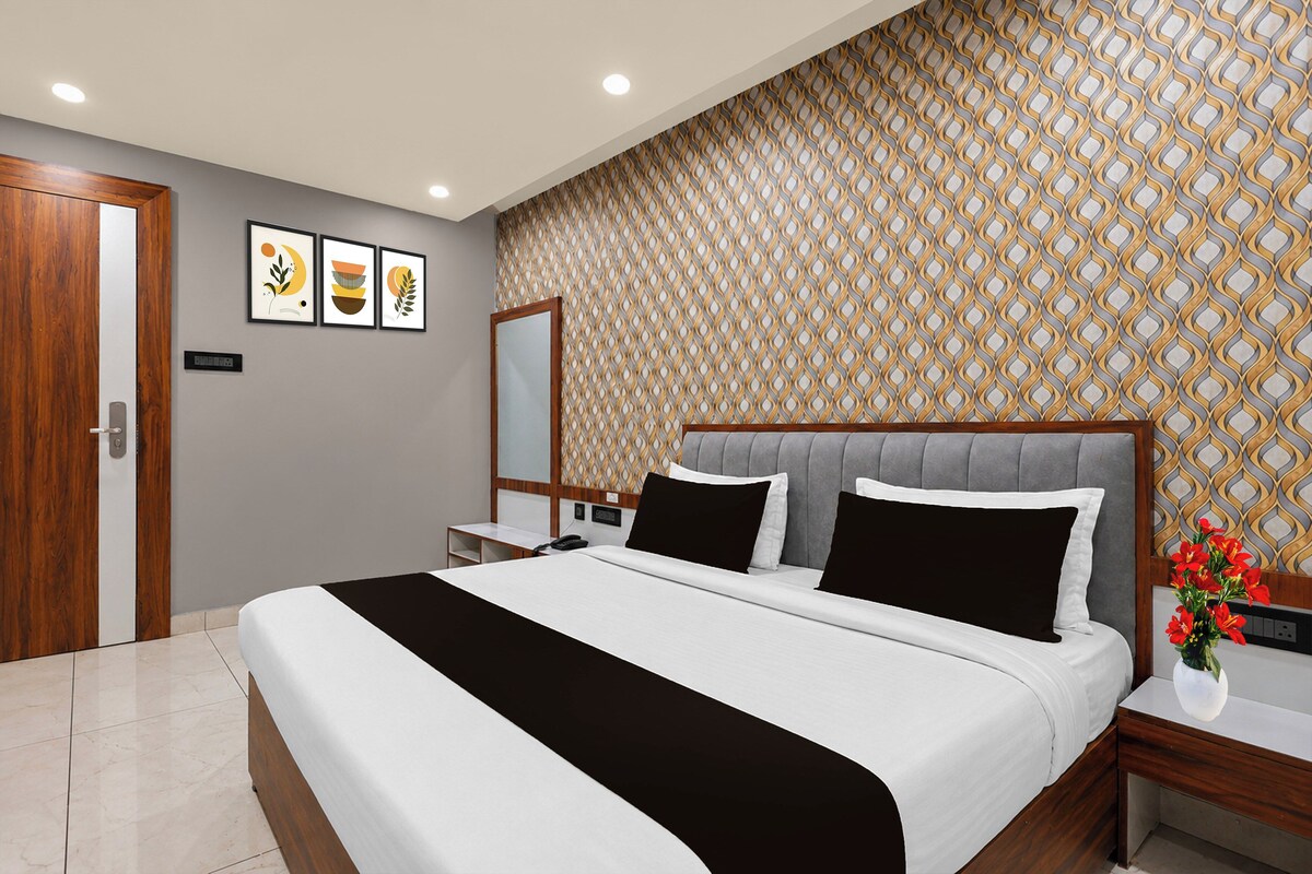 A modern bedroom with a large bed, a nightstand, a mirror, and a patterned wallpaper.
