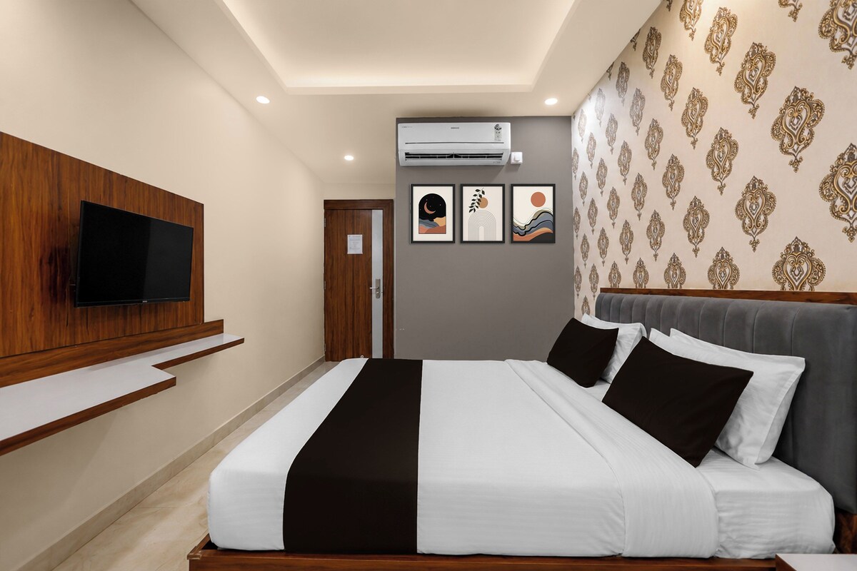 Habitación de hotel con cama, televisión montada, equipo de aire acondicionado y decoración en la pared.