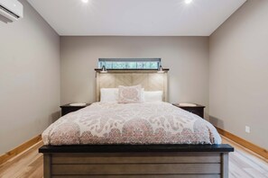 A bedroom with a bed, nightstands, a headboard with a window, and a ceiling fan. - Luxury Pines Retreat at Black Butte Ranch (Sisters)