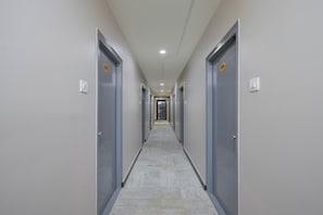 Un pasillo con puertas a ambos lados, suelo de baldosas e iluminación empotrada en el techo.