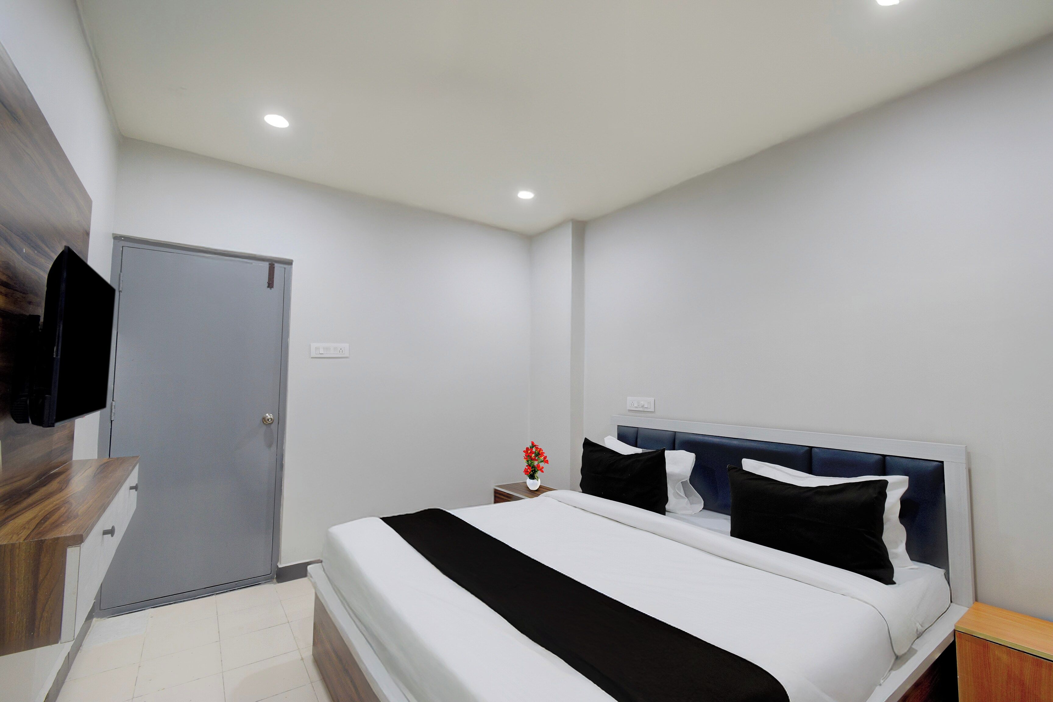 Una habitación de hotel moderna con una cama, una mesita de noche y una pequeña mesa con un florero.