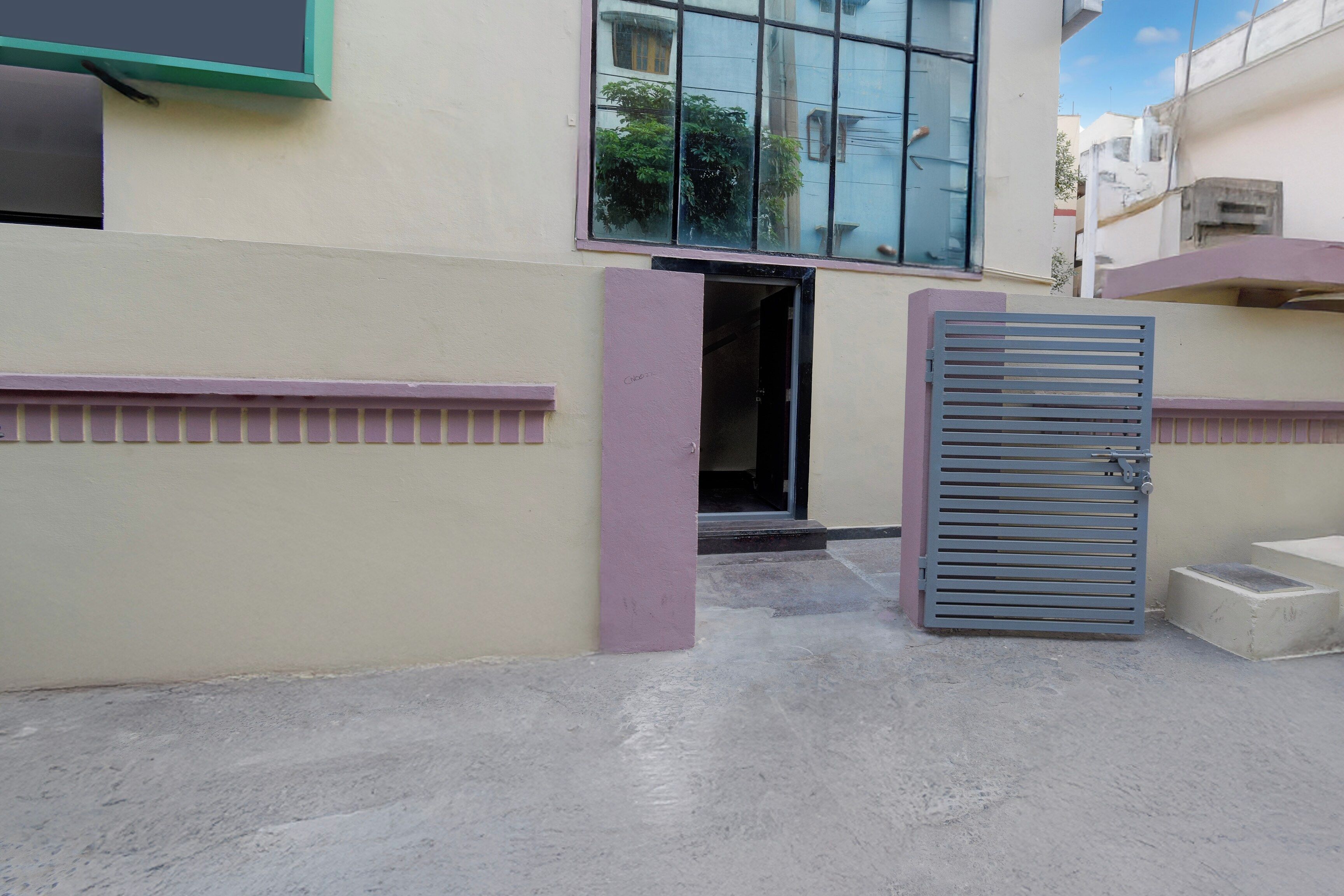 Una entrada de edificio con una puerta metálica y unos pocos escalones que llevan a la puerta.