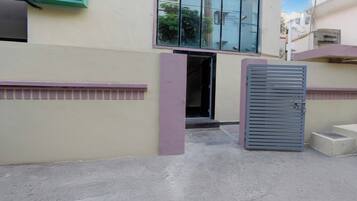 Una entrada de edificio con una puerta metálica y unos pocos escalones que llevan a la puerta.