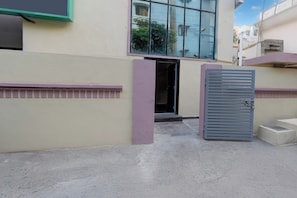 Una entrada de edificio con una puerta metálica y unos pocos escalones que llevan a la puerta.