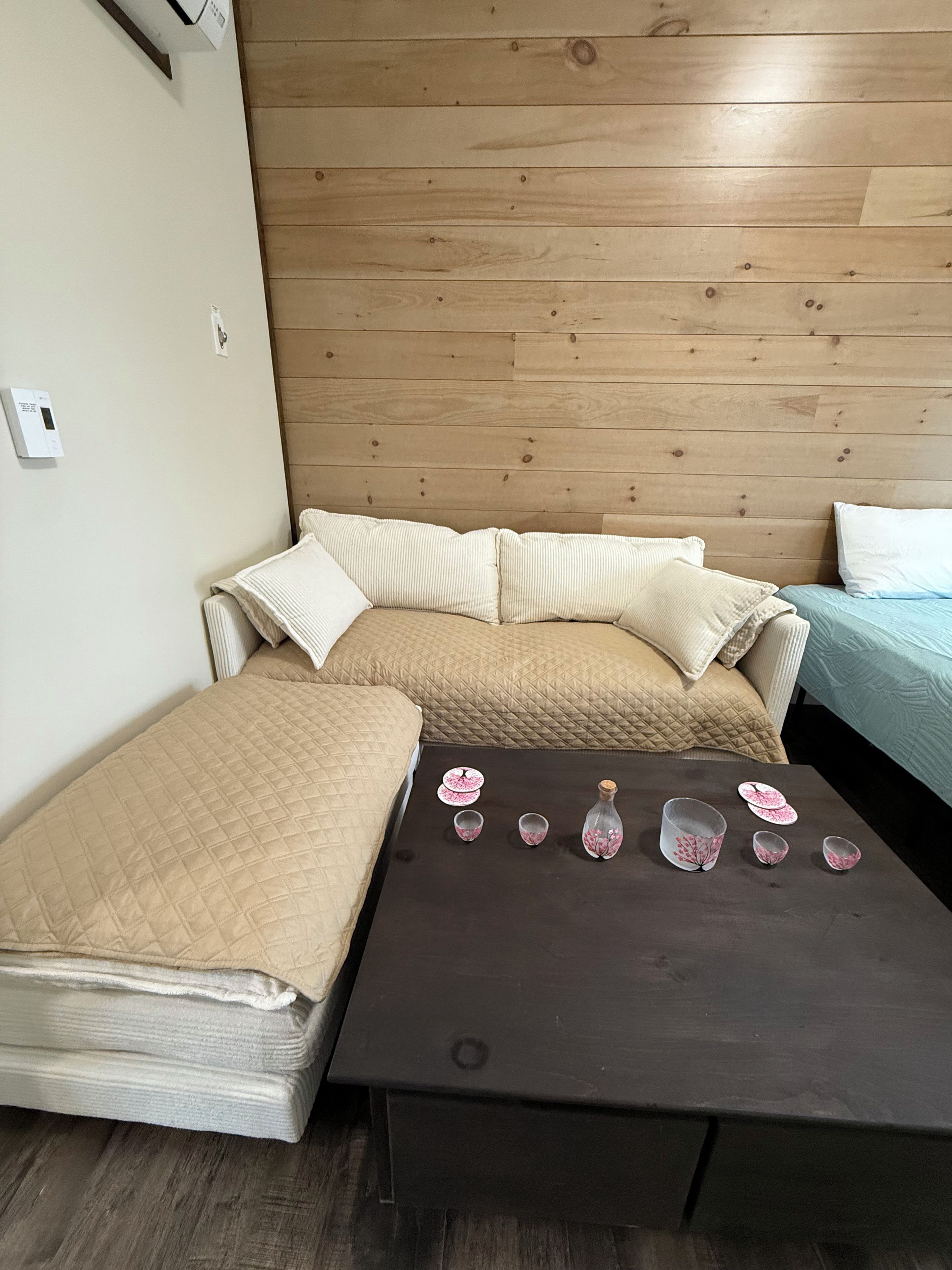 Quarto com cama, sofá, mesa e ar condicionado instalado na parede.