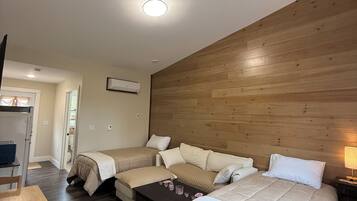 Ein Zimmer mit einem Holzkopfteil, einem Bett mit weißer Bettdecke, einem Holztisch und einem Stuhl.