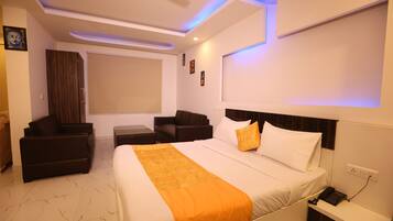 Una habitación de hotel con cama, escritorio, silla, sofá y ventana.