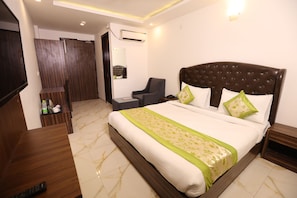 Habitación de hotel con cama, silla, escritorio, televisor y aire acondicionado.