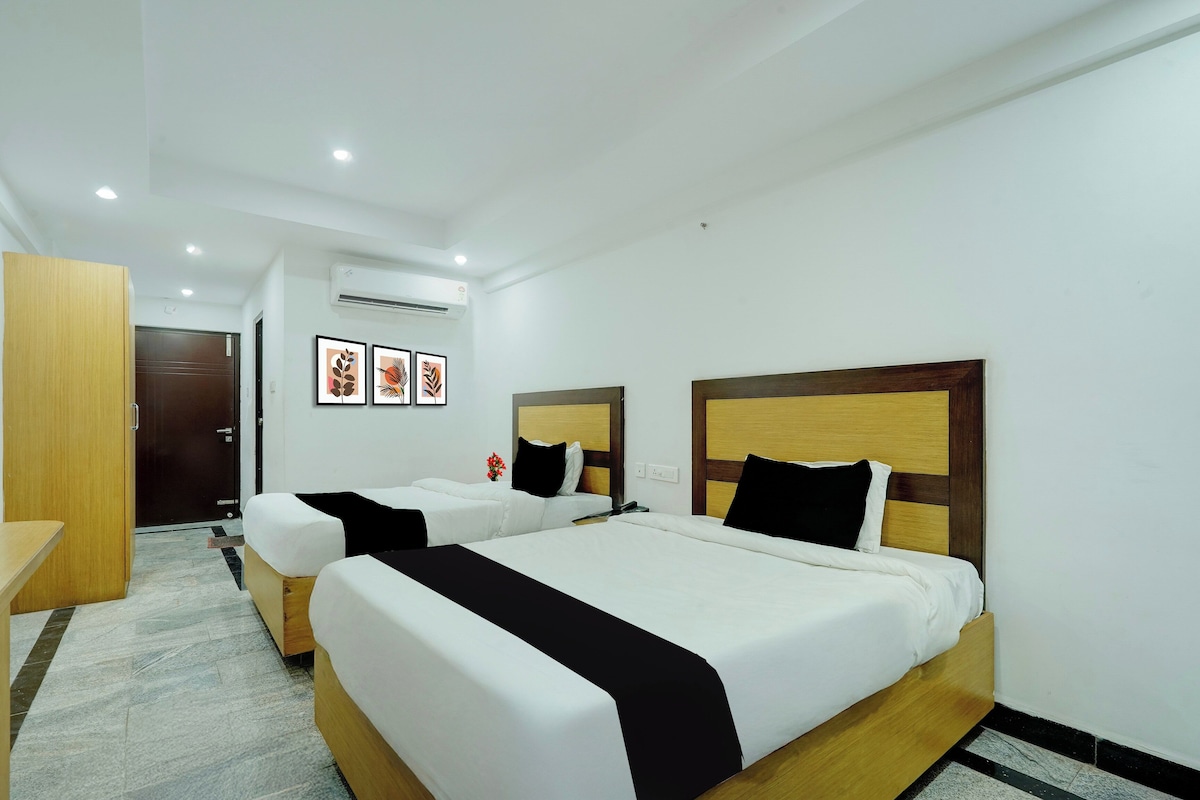 Habitación de hotel con dos camas, un armario de madera, un escritorio y una mesita.