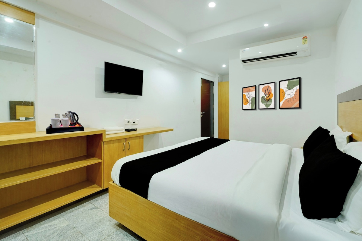 Una habitación de hotel con cama, televisor, escritorio y estante.